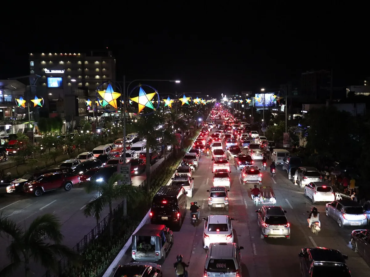Night traffic jam on Diversion Road in Iloilo City, cars and jeepneys bumper to bumper under Christmas star lanterns